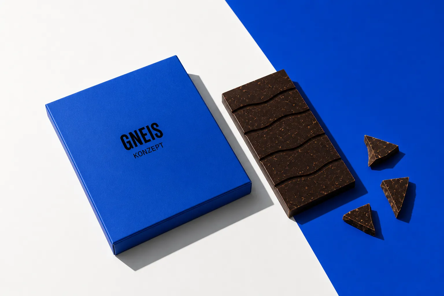 Ultramarine GNEIS Konzeptschachtel neben einer dunklen Schokoladentafel und einzelnen Bruchstücken.